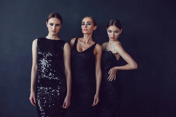 Chicas atractivas en vestidos de cóctel negro sobre un fondo oscuro . — Foto de Stock