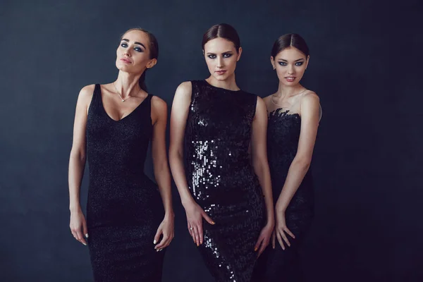 Chicas atractivas en vestidos de cóctel negro sobre un fondo oscuro . — Foto de Stock