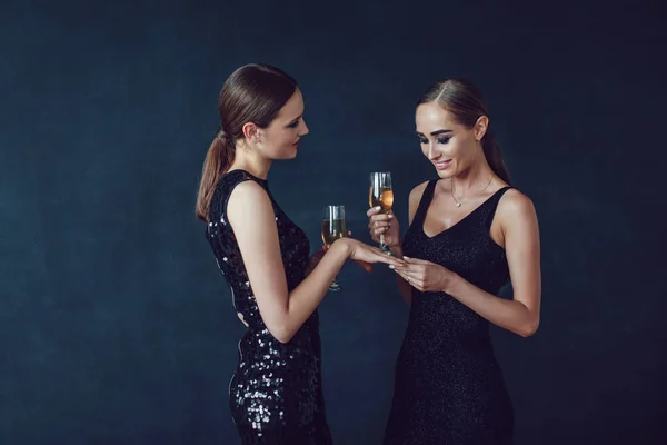 Привабливі жінки в коктейльних сукнях тримають келихи шампанського, розмовляють і посміхаються . — стокове фото