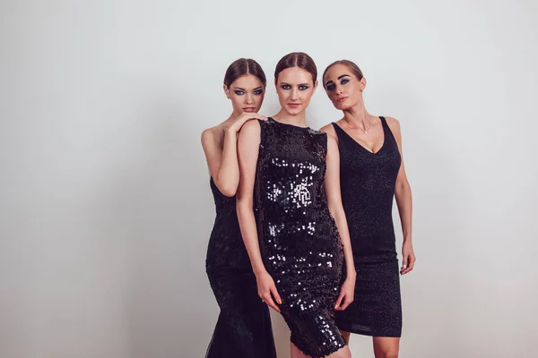 Attractive girls in black cocktail dresses on a grey background. — Stock Photo, Image