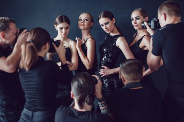 Fotoğrafçılar paparazzi kokteyl elbiseleri koyu arka plan üzerinde kadın fotoğrafları almak.