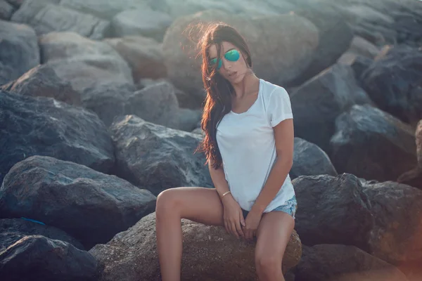 Meisje in een wit t-shirt en zonnebrillen op de achtergrond van de stenen. Mock-up. — Stockfoto