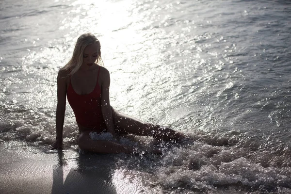 Sexy dívka leží v červených plavkách u oceánu. — Stock fotografie
