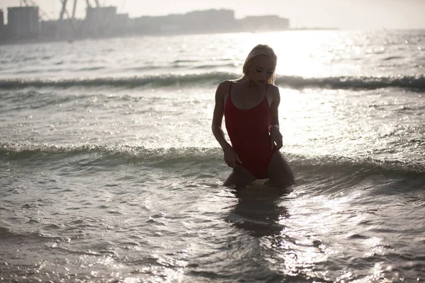 Sexy meisje staat in een rood badpak in de Oceaan. — Stockfoto