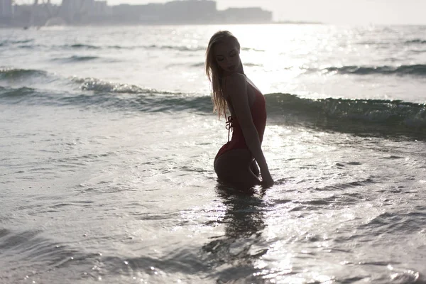 Sexy meisje staat in een rood badpak in de Oceaan. — Stockfoto