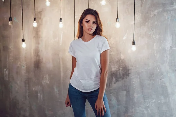 Seksi kadın ampuller ile gri bir arka plan üzerinde beyaz bir tişört. Mock-up.