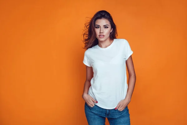 Szexi nő a narancssárga háttér fehér póló. Modell. — Stock Fotó