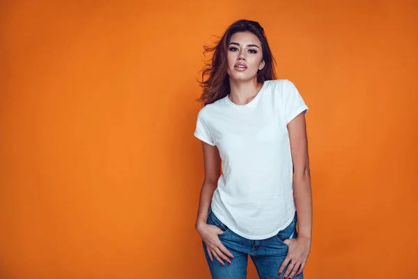 Sexy woman in a white T-shirt on the orange background. Mock-up. — Stock Photo, Image