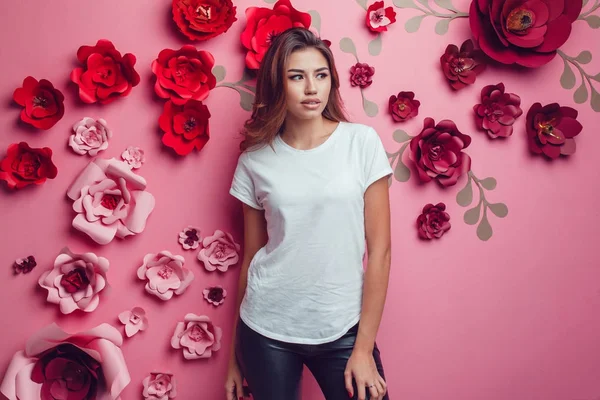 Szexi nő egy fehér pólót, egy rózsaszín háttér, virágok. — Stock Fotó