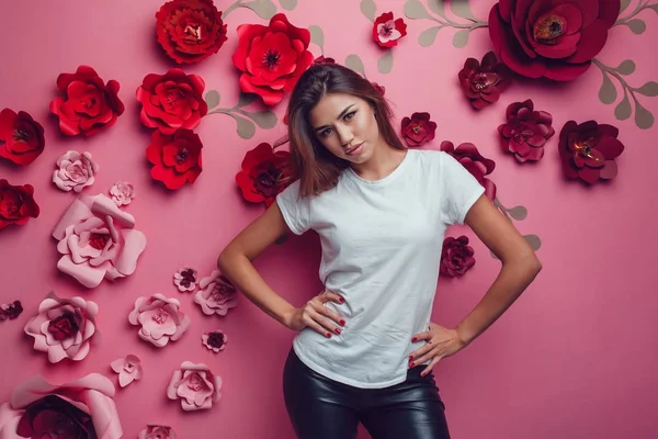 花とピンクの背景に白い t シャツを着たセクシーな女性. — ストック写真