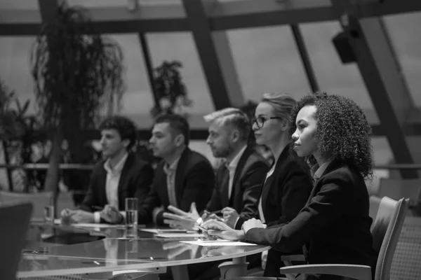 Een groep van mensen uit het bedrijfsleven zitten aan een tafel in een lijn en debatteren. — Stockfoto