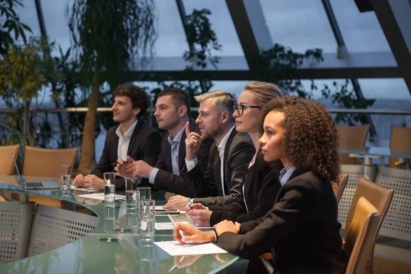 Een groep van mensen uit het bedrijfsleven zitten aan een tafel in een lijn en debatteren. — Stockfoto