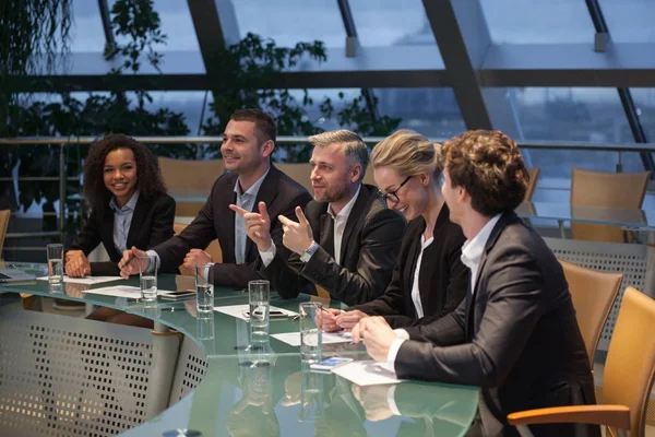 Egy csoport üzleti ember ül az asztalnál megvitatása és nevetve. — Stock Fotó
