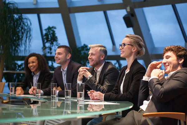 Een groep van mensen uit het bedrijfsleven zitten aan een tafel bespreken en lachen. — Stockfoto