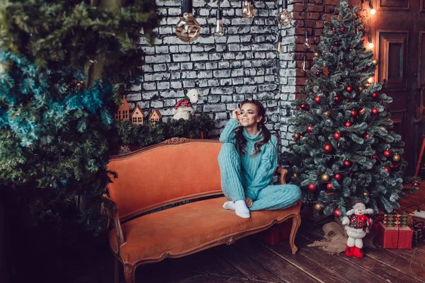 美丽的女方坐在靠近圣诞树的沙发上。新年. — 图库照片