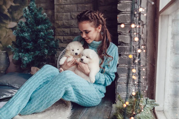 Привлекательная девушка сидит дома с милыми щенками на руках. Рождество . — стоковое фото
