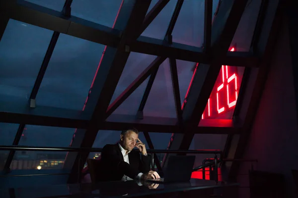 Businessman working on laptop in night office.