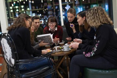 Pozitif gençler grup bir akıllı telefon kullanmak ve bir kafede vakit.