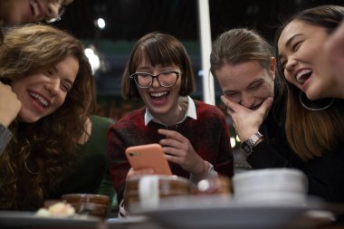 Pozitif gençler grup bir akıllı telefon kullanmak ve bir kafede vakit.