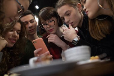 Pozitif gençler grup bir akıllı telefon kullanmak ve bir kafede vakit.