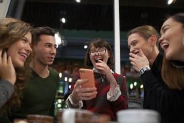 Pozitif gençler grup bir akıllı telefon kullanmak ve bir kafede vakit.