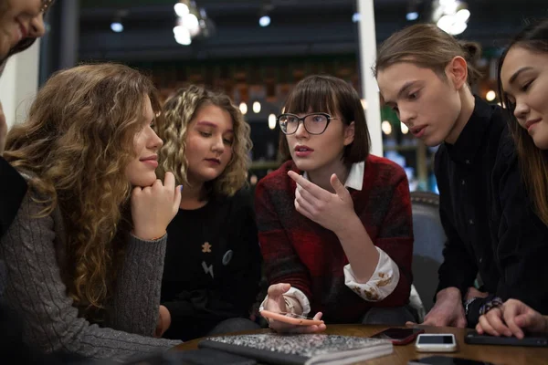 Gruppe positiver Teenager nutzt Smartphone und verbringt Zeit in einem Café. — Stockfoto