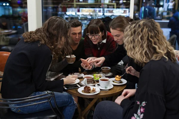 Grupa nastolatków pozytywny za pomocą smartfona i spędzić czas w kawiarni. — Zdjęcie stockowe
