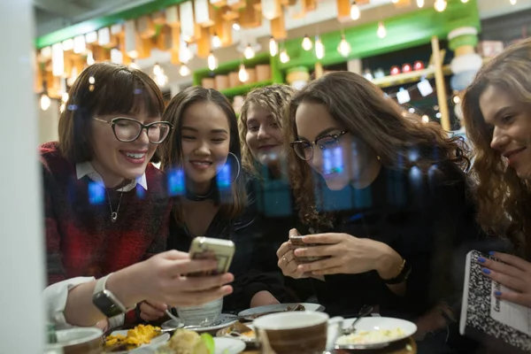 Pozitif gençler grup bir akıllı telefon kullanmak ve bir kafede vakit.