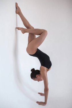 Beyaz bir arka plan üzerinde jimnastik bir pozisyonda genç kadın jimnastikçi standları.