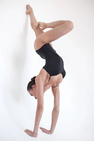 Молода жінка-гімнастка стоїть в гімнастичному положенні на білому тлі . — стокове фото