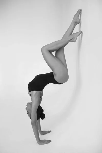 Молода жінка-гімнастка стоїть в гімнастичному положенні на білому тлі . — стокове фото