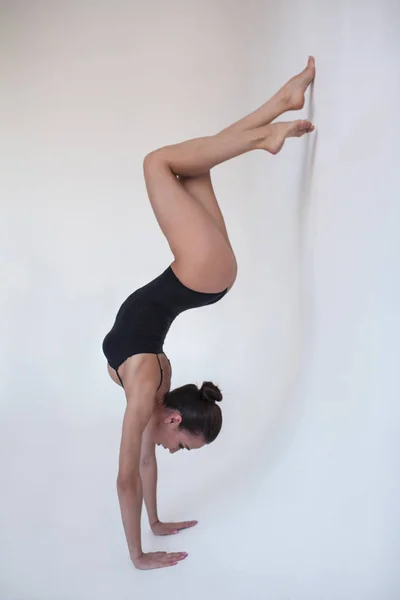 Giovane ginnasta donna si trova in una posizione ginnica su uno sfondo bianco . — Foto Stock