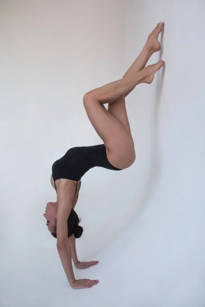 Mujer joven gimnasta se encuentra en una posición gimnástica sobre un fondo blanco . —  Fotos de Stock