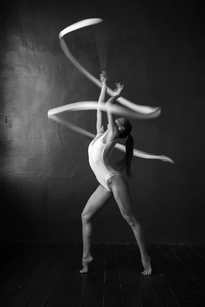 Krásná žena gymnastka s bílou mašlí na černém pozadí. — Stock fotografie