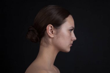 Siyah bir zemin üzerine makyaj olmadan bir kadının yüz profili.