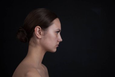 Siyah bir zemin üzerine makyaj olmadan bir kadının yüz profili.