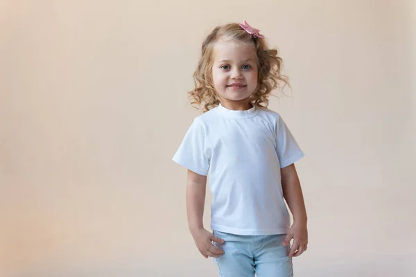 Cute little girl in a white t-shirt on a light background. Mock-up. — Stock Photo, Image
