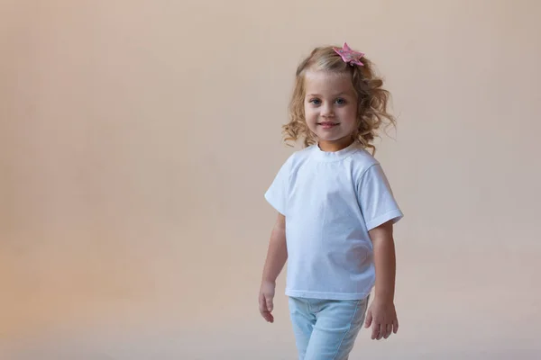 Roztomilá holčička v bílé tričko na světlém pozadí. Maketa. — Stock fotografie