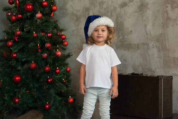 Jolie petite fille dans un T-shirt blanc est debout près du sapin de Noël. Maquette . — Photo