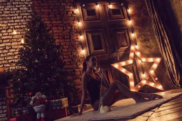 Sexy woman lying on the floor and talking on the phone against the backdrop of the Christmas tree. — Stock Photo, Image