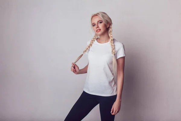 Hermosa chica con dos trenzas en una camiseta blanca. Mock-up . —  Fotos de Stock