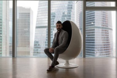 Modern bir ofiste bir sandalyede oturan iş adamı.