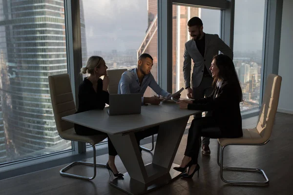 Mensen uit het bedrijfsleven werken in een kantoor op een achtergrond van panoramische ramen. — Stockfoto