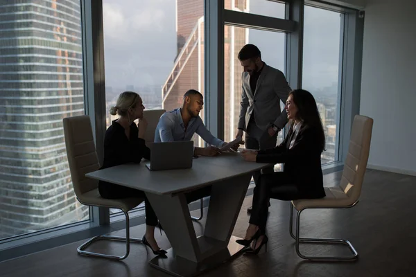 Mensen uit het bedrijfsleven werken in een kantoor op een achtergrond van panoramische ramen. — Stockfoto