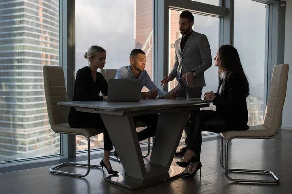 Mensen uit het bedrijfsleven werken in een kantoor op een achtergrond van panoramische ramen. — Stockfoto