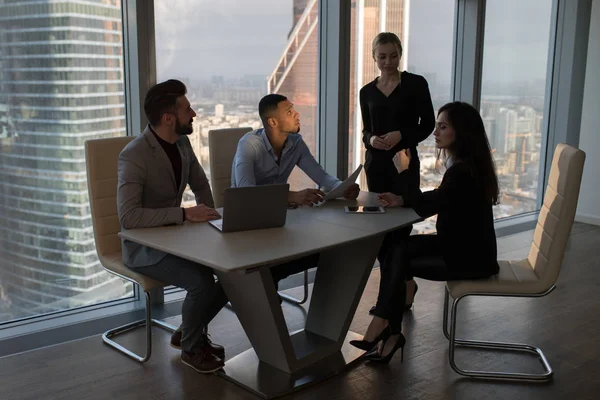 Mensen uit het bedrijfsleven werken in een kantoor op een achtergrond van panoramische ramen. — Stockfoto