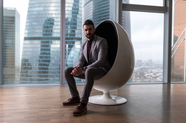 Modern bir ofiste bir sandalyede oturan iş adamı.