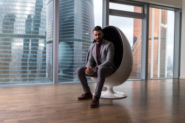 Modern bir ofiste bir sandalyede oturan iş adamı.