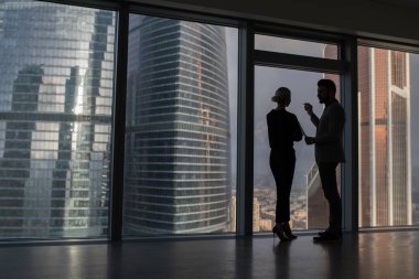 Büyük şehir binaları ile büyük panoramik pencere yakınındaki müzakere ayakta konuşurken iş adamları.