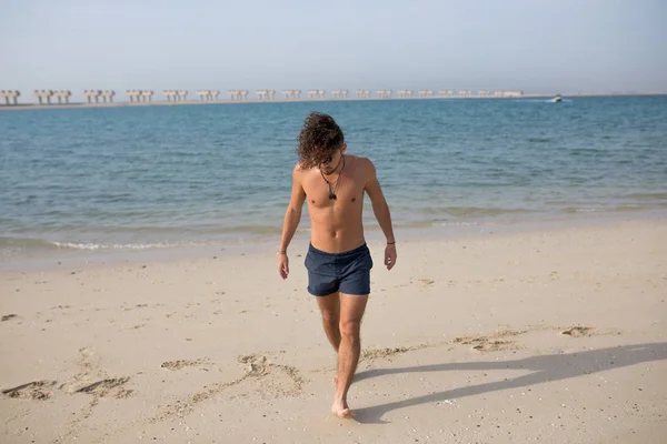 Jeune homme aux cheveux bouclés sur la plage . — Photo